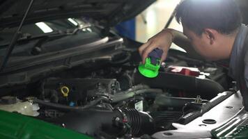 A man is working on a car engine. He used a flashlight to check for abnormalities in the engine. video