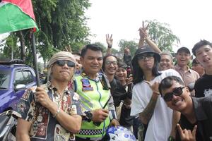 A group of young Asian men are talking to a traffic policeman. Indonesia - Medan, 21 June 2024 photo
