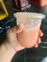 someone is holding a plastic cup with tamarillo juice in it photo