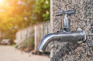 modern metal outdoor faucet with clean drinking water in park on street in city in summer on a sunny day close-up photo
