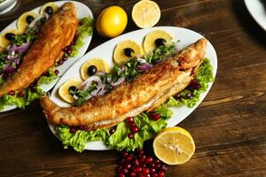 Fried Fish With Lemon and Pomegranate on Wooden Table photo