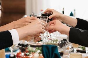 hands of people toasting and clinking glasses at a celebration photo