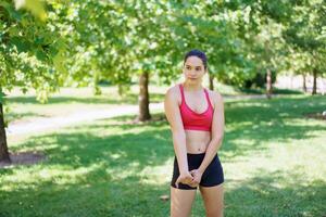 Young woman exercises outdoors in a park, showing determination and commitment to fitness under sunny skies photo