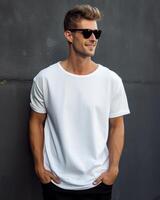 Man in white t-shirt against grey wall, hands in pockets photo