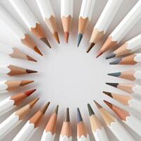 White pencils arranged in a circle on a light surface, showcasing a rainbow of colors photo