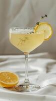 Cocktail glass with yellow drink, lemon slice, thyme sprig photo