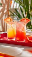Two vibrant cocktails with grapefruit garnish on a red tray photo