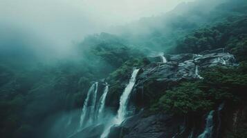 Waterfalls cascade down a misty, forested mountainside photo