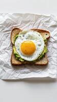 A single slice of avocado toast topped with a sunny-side up egg photo