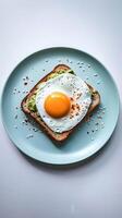 A perfectly cooked egg sits atop avocado toast on a blue plate photo