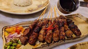 Beef Satay marinated with spice and sweet soy sauce, locals called it Satay Maranggi coriander beef satay, served on plate with onion, chilli, soy sauce and tomato. Indonesian food video