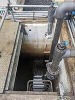 Looking Down into an Open Manhole Water Drainage System Power plant. A close-up view looking down into an open manhole revealing the dark depths below. photo