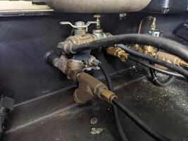 Close-up of solenoid valve of drainage air compressor. A close-up view of plumbing valves and piping under a sink, showcasing the intricate connections and details of the system. photo
