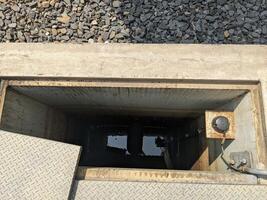 Looking Down into an Open Manhole Water Drainage System Power plant. A close-up view looking down into an open manhole revealing the dark depths below. photo