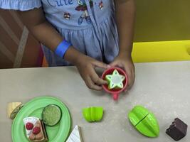 Child Playing with Play Food. A young child playing with plastic toy food, setting a table with cakes and fruit. photo