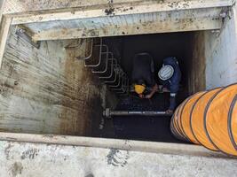 Two Workers Inspecting a Pipe Inside a Concrete Structure Confine space photo