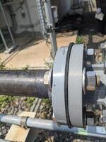 Close-up of Pipe Joint. A close up view of a pipe connection, showing the metal pipe, weld, and the nuts and bolts securing the joint. photo