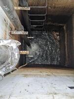 Looking Down into an Open Manhole Water Drainage System Power plant. A close-up view looking down into an open manhole revealing the dark depths below. photo