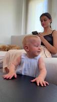 A mother and child relaxing at home, with the baby curious about the smartphone in a cozy setting video