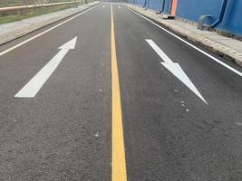 Road Marking with a White Arrow. A close-up view of white painted arrows on a grey asphalt road. The arrows indicate direction and guidance for vehicles. photo