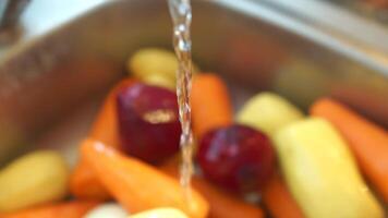 Vegetables in the sink, hands wash vegetables under a stream of water from a tap. Preparation Ukrainian borscht, peeled carrots, beets, and potatoes are seen being washed in a sink. video