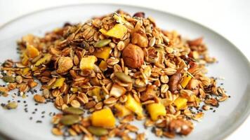 Healthy organic granola breakfast flakes with almonds, cashew nuts walnuts, hazelnuts, pumpkin seeds and cranberries circle rotation close up top view. video