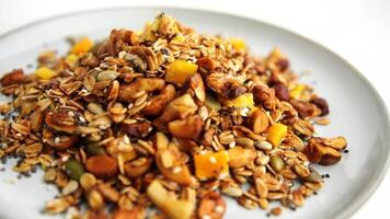 Healthy organic granola breakfast flakes with almonds, cashew nuts walnuts, hazelnuts, pumpkin seeds and cranberries circle rotation close up top view. video