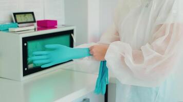 Doctor is putting on gloves to take tools from sterilization machine. video