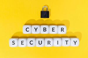 Cyber security concept. Text on blocks and padlock on yellow background photo