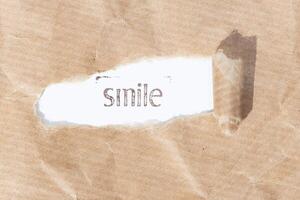 Smile message. Brown paper torn stripe with text on white paper background photo