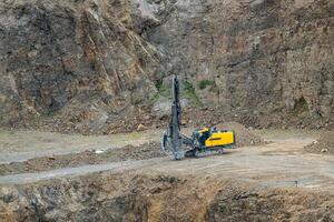 Opencast mining quarry with mining drilling machine. Mining in the granite quarry. Mining industry. photo