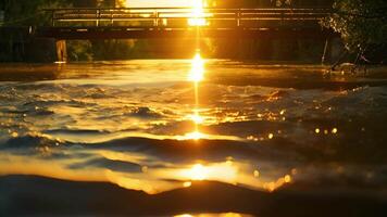 A panoramic view of a golden sunset reflecting off the surface of a river with a solarpowered bridge in the background video