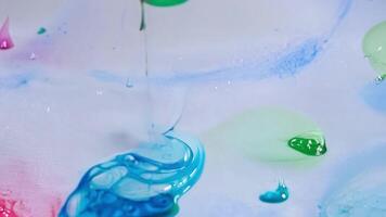 Drops of dye fall like raindrops onto the fabric below creating a mesmerizing pattern.. video