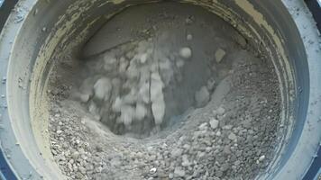 Small pebbles and gravel are added to the cement mixer creating a textured and durable concrete.. video
