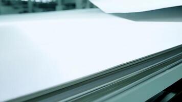 A closeup of a finished sheet of paper its smooth surface glinting in the factorys bright lights.. video
