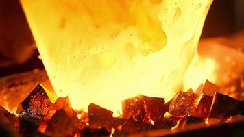 Closeup of molten glass being dipped into crushed glass shards creating a textured and vibrant outer layer for a stunning glass sculpture.. video