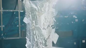 Cascading waterfalls of recycled paper scraps pouring into a massive bin.. video