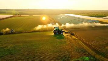 A tractor is plowing a field with a sun in the background video