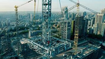 A large construction site with cranes lifting beams, workers in hard hats coordinating tasks. video