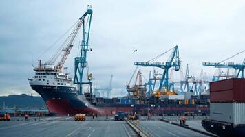 A cargo ship docked at a port, cranes loading and unloading containers. video