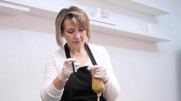 A woman confectioner cuts off the tip of a pastry bag with cream for further use. video