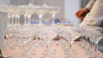Empty wine or champagne glasses on table are in pyramid. The waiter arranges glasses in a pyramid video