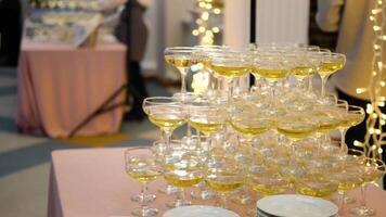 A pyramid of champagne glasses at a party against the backdrop of a hall with guests. champagne pyramid video