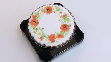 Gingerbread with white icing and floral pattern spins on a plastic tray. An example of a confectioner work. View from above. video