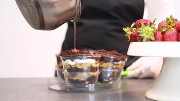 Confectioner pouring hot chocolate over layered dessert in transparent form video