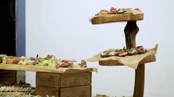 Buffet table with cold appetizers. Meat and vegetable snacks are placed on wooden stands video