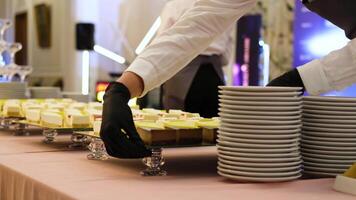A waiter in black gloves puts a mirrored tray of cheesecakes on the table video