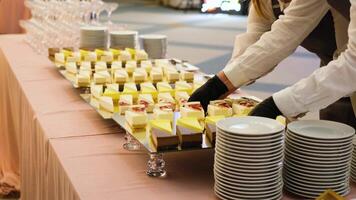 A waiter in black gloves puts a mirrored tray of cheesecakes on the table video