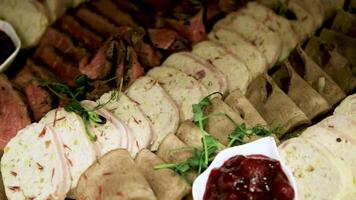 Meat platter on a wooden tray. Cold appetizer of chicken roll, beef tongue, beef with sauce video