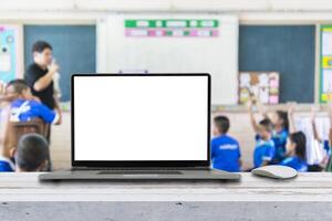 Computer on the table, blur image of children in the classroom photo